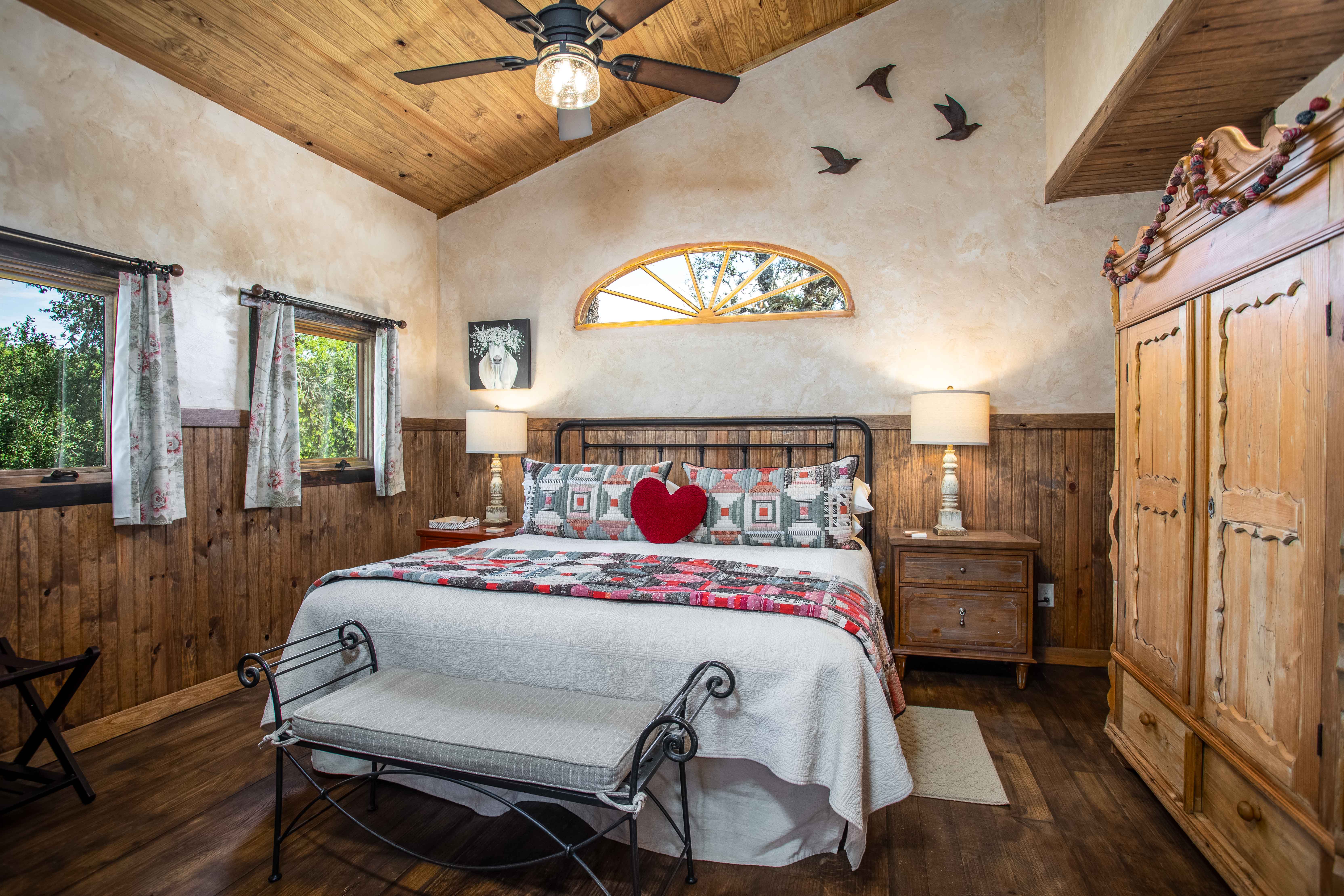 A wide view of a cozy room with a bed, bench, and window.