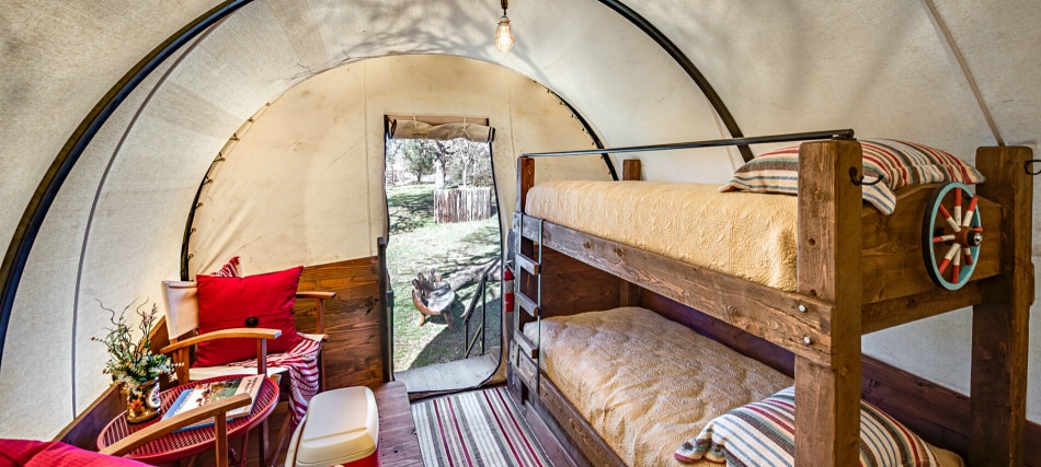 A cozy glamping room with bunk beds, a chair, and a table.