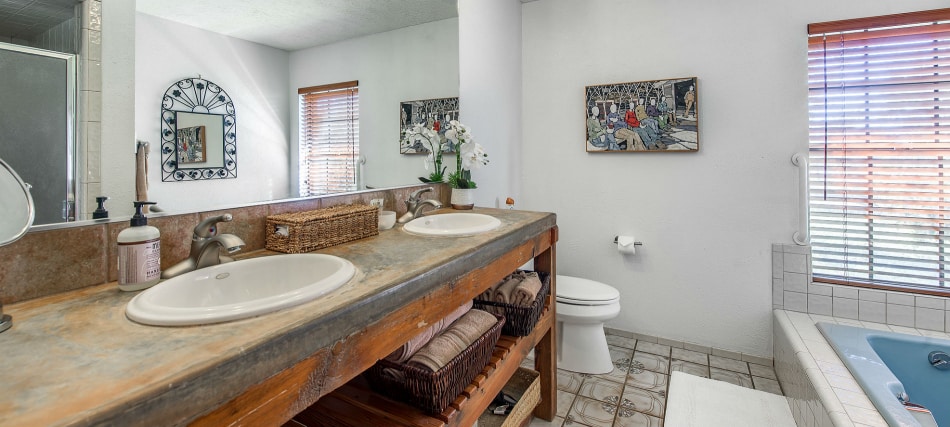 A clean and well-appointed bathroom with a double vanity, toilet, and jacuzzi tub.
