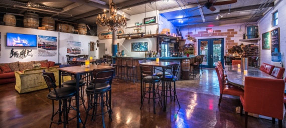 A dimly lit bar area with tables, chairs, and a bar counter.