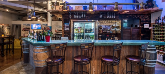 A bar with a blue countertop, wooden base, and several stools.