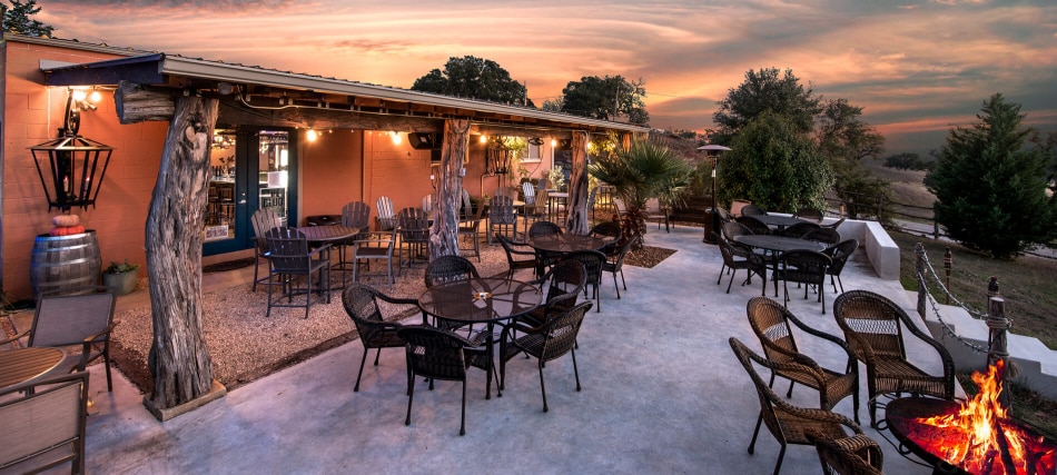 A patio area with outdoor seating and a fire pit at dusk.